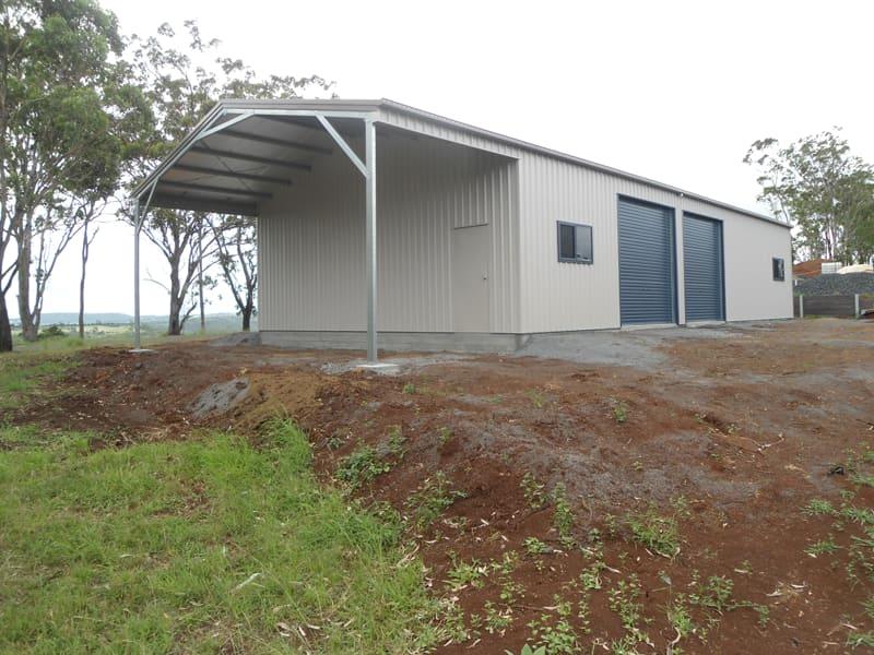 Zincalume steel shed with a large gable awning standing on a freshly prepared earth pad on a rural block