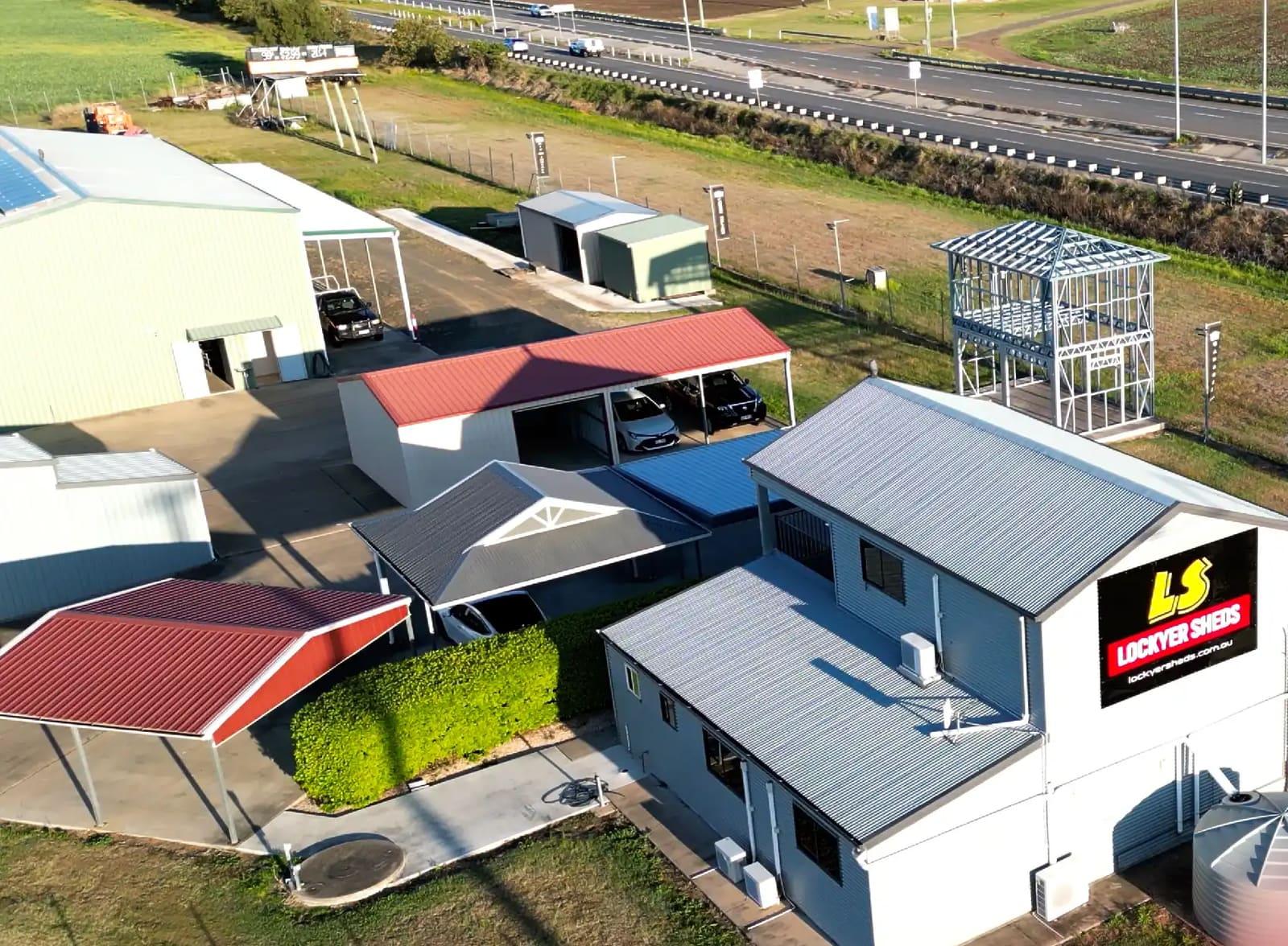 Aerial view of the Lockyer Sheds display yard with the company sign, display sheds and a standing steel frame